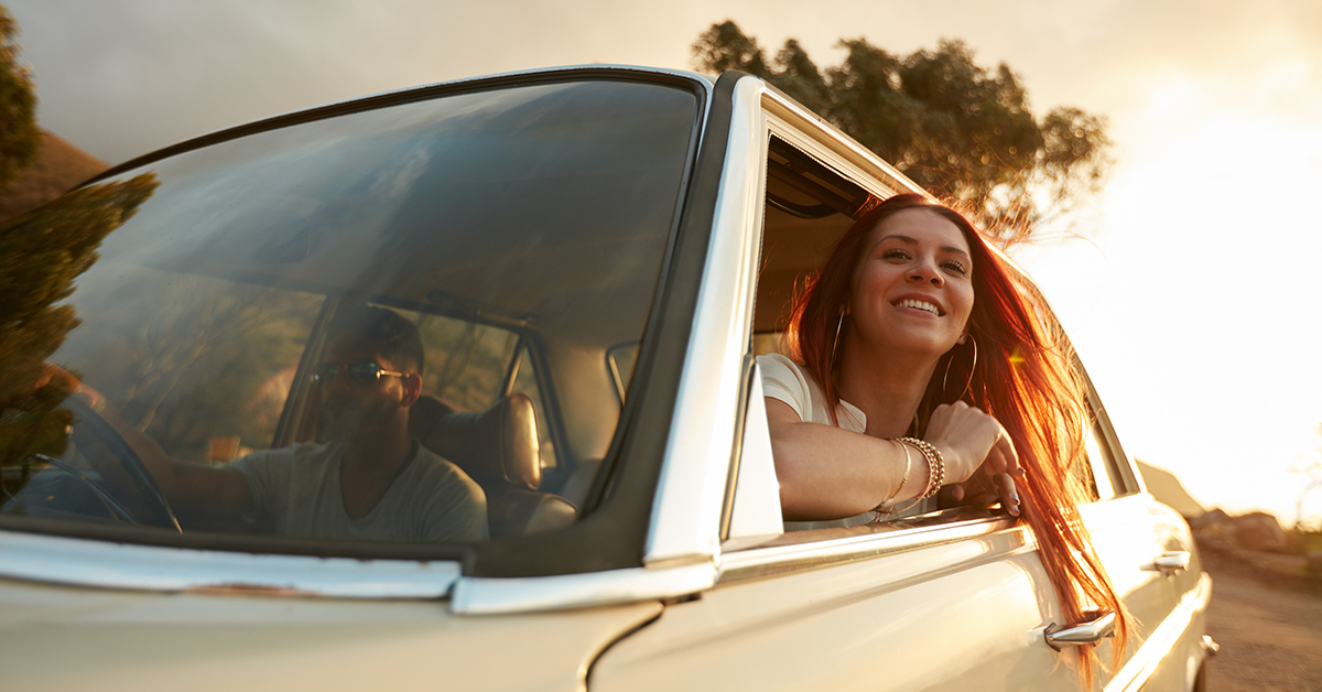 A woman is smiling from a window of a car.