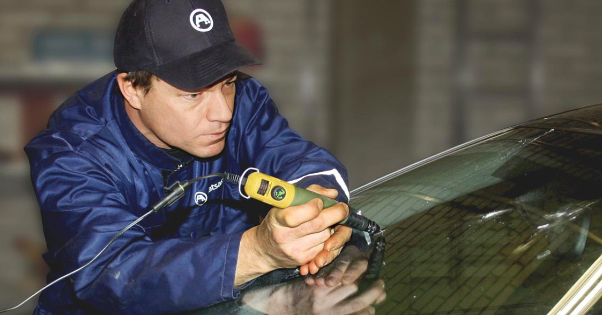 An A-Katsastus inspector is repairing a windshield.