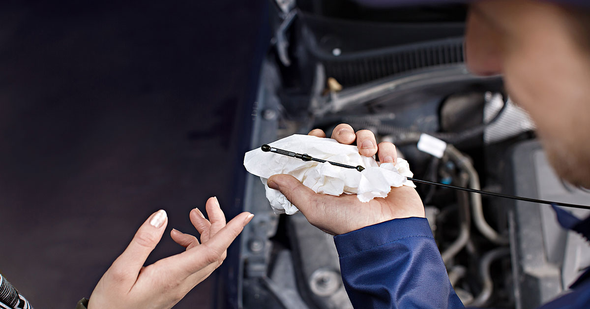 An A-Katsastus inspector measures the engine oil level.