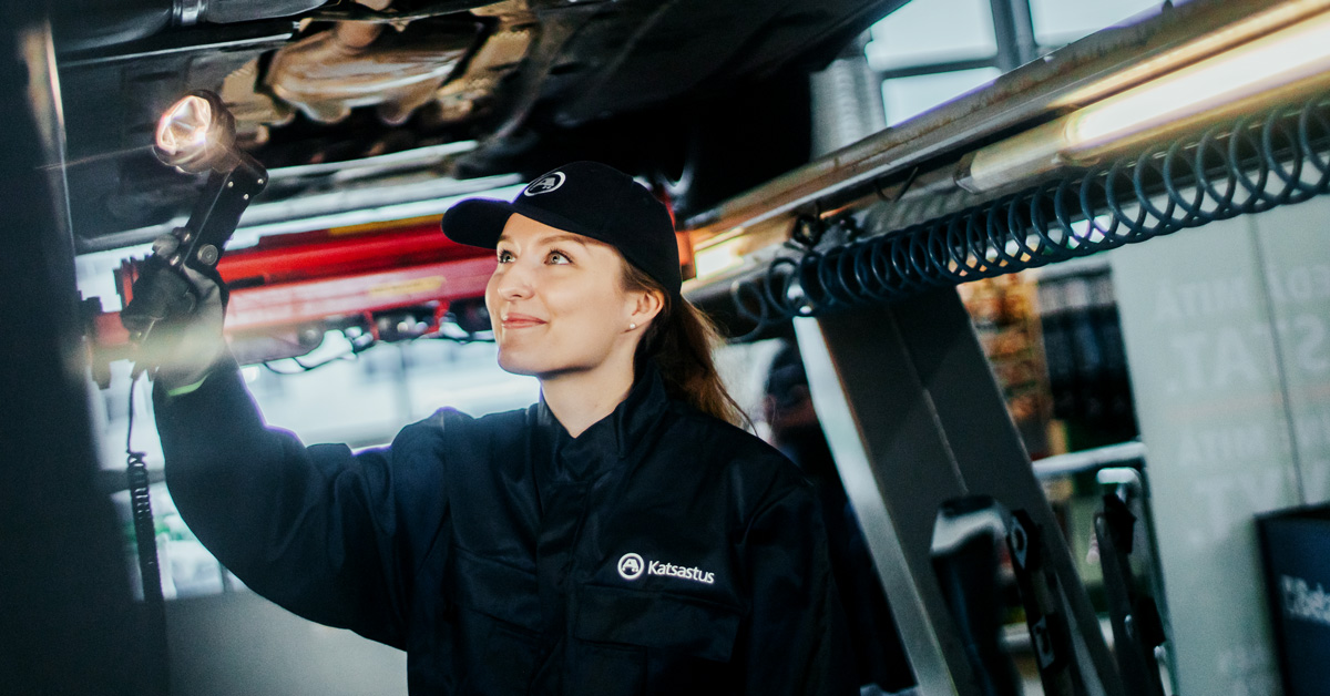 An A-Katsastus inspector examining the underside of a vehicle.