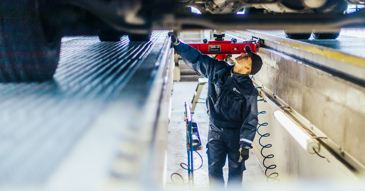 An A-Katsastus inspector checking the chassis of a heavy vehicle.