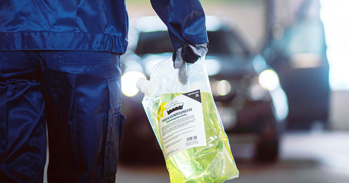 An A-Katsastus inspector holds a screenwash fluid bag.