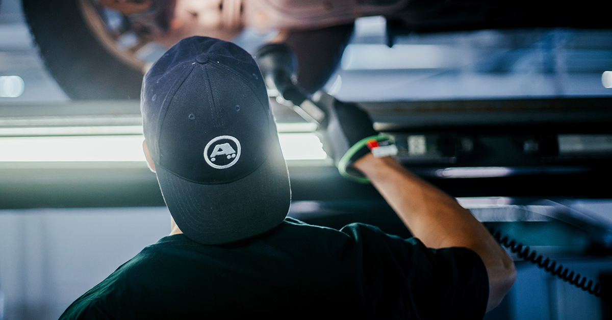 An A-Katsastus inspector checking the underside of the vehicle.