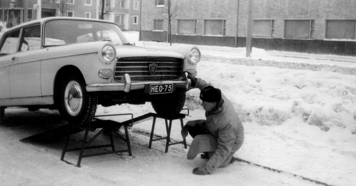 Vanha auto ajettuna pukeille ja katsastaja tutkii sen pohjaa.