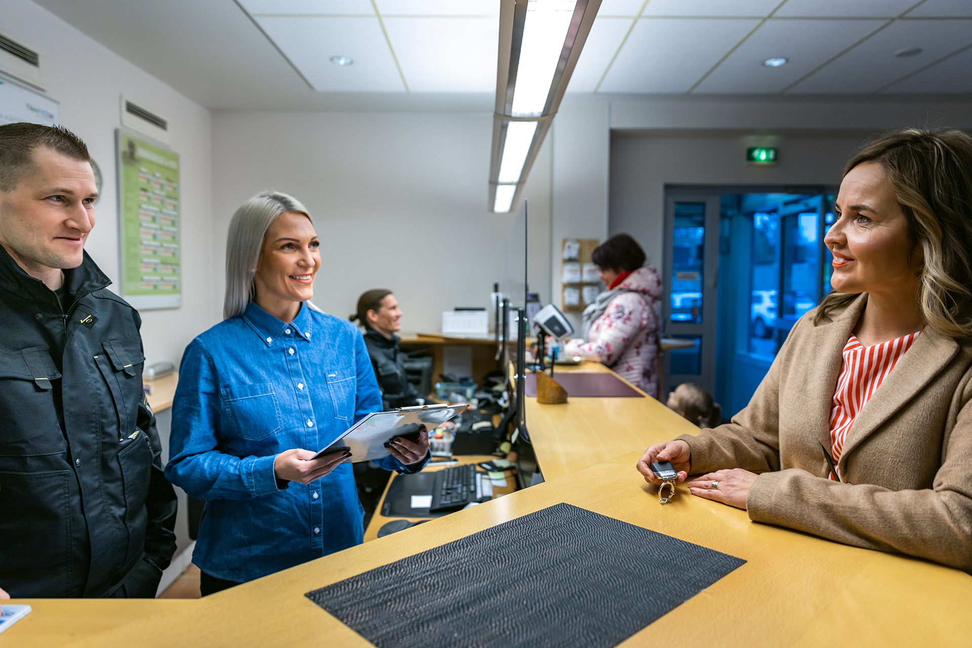 Asiakas Katsastajasi.fi-aseman toimistossa palveluneuvojan ja katsastajan kanssa.